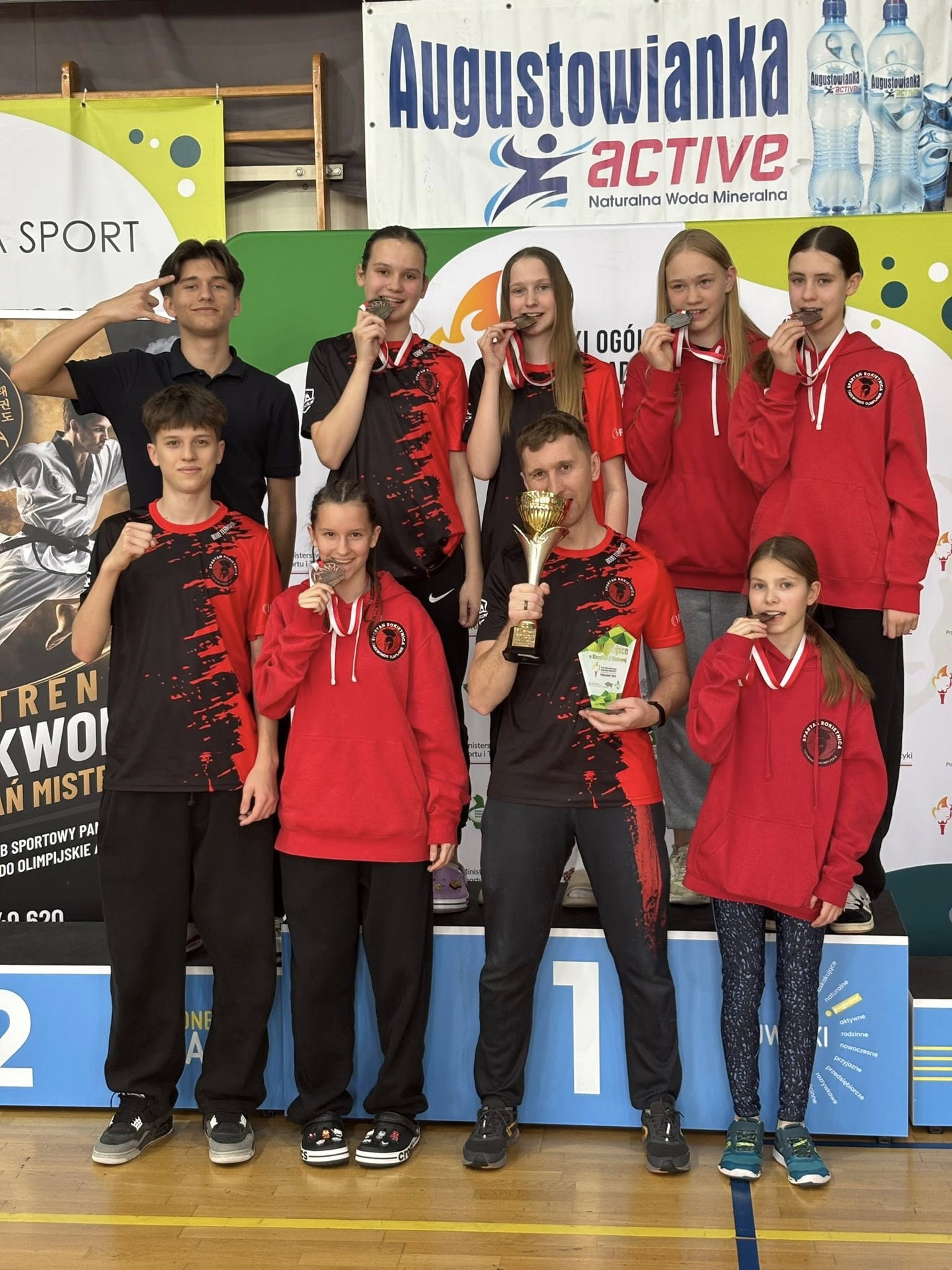 Zawodnicy taekwondo na podium wraz z trenerem